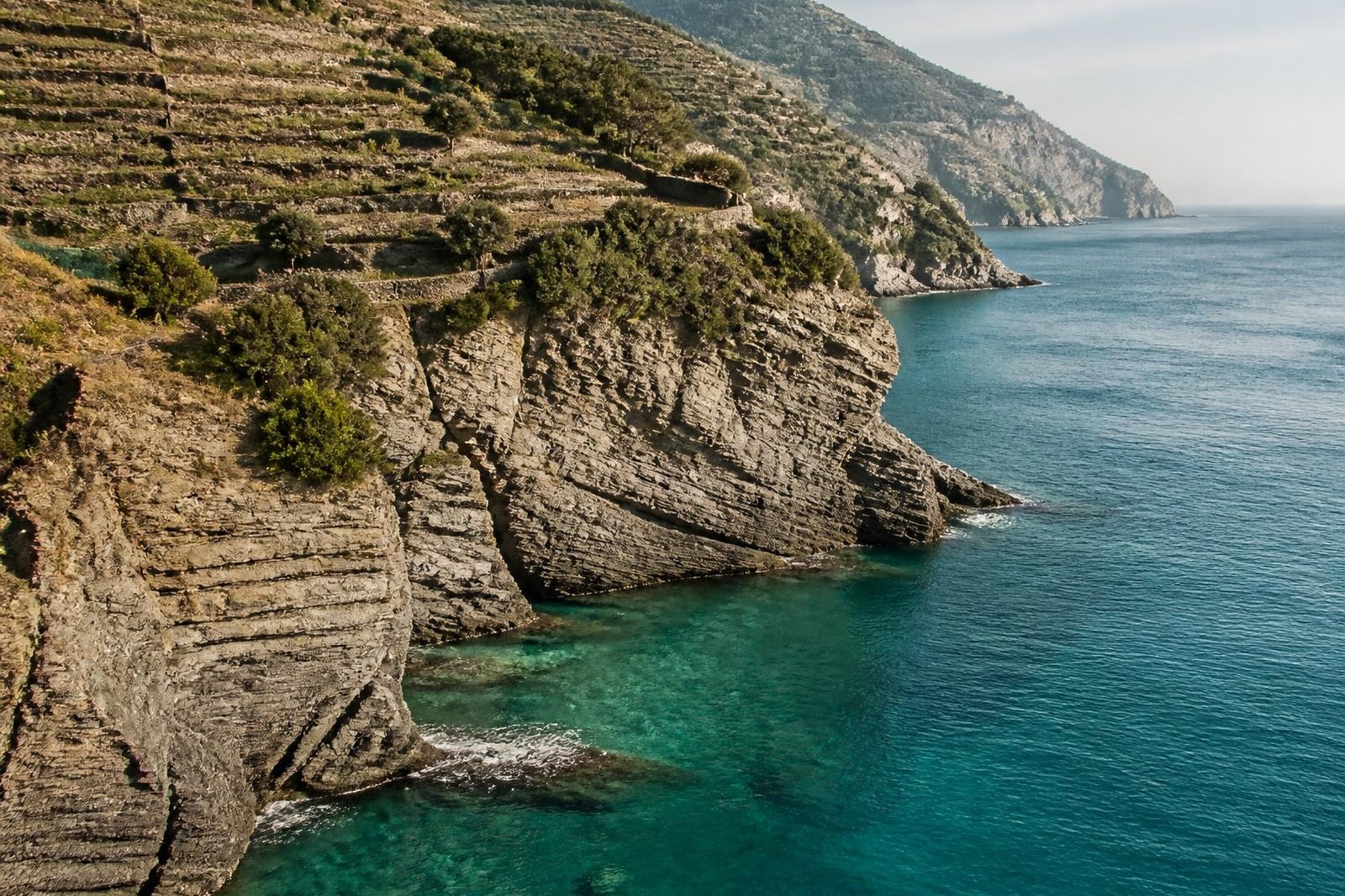 Terraced limestone cliffs above clear turquoise water on the Ligurian coast